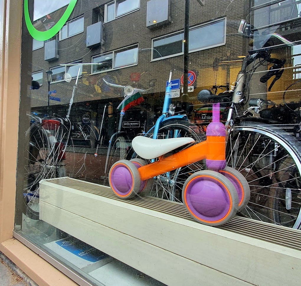 Een loopfietsje in de etalage van Just Bike, met de fietsen in de winkel erachter