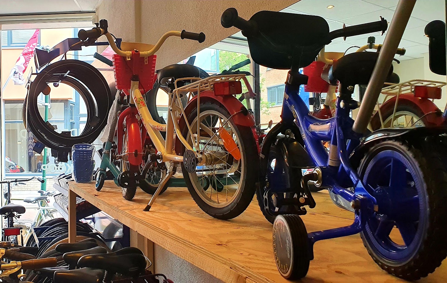 Kinderfietsen met zijwieltjes op een houten plank in de winkel